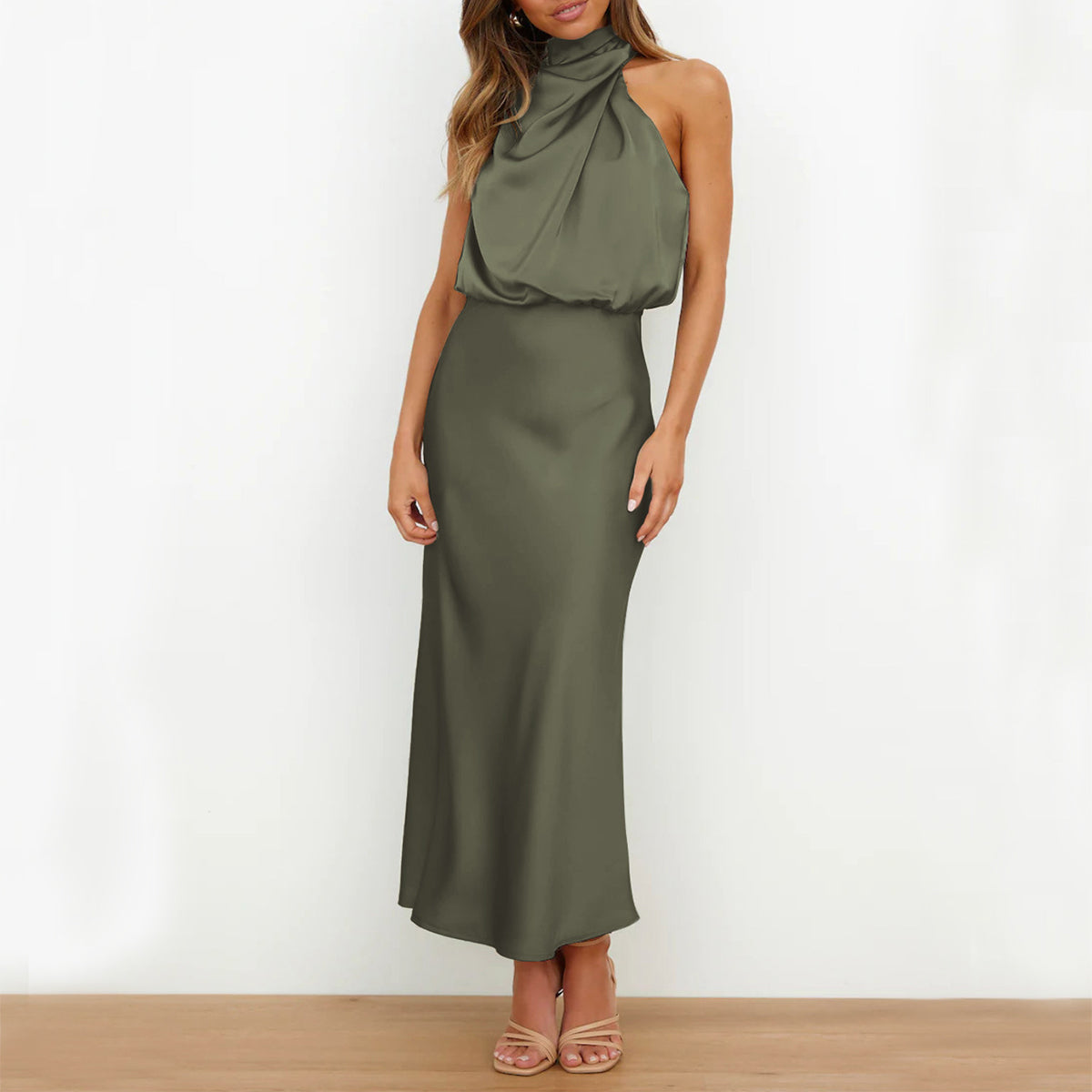 Woman wearing an olive green halter neck dress against a white background