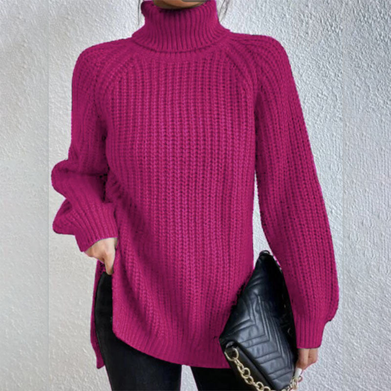Person wearing a bright pink knitted sweater holding a black handbag against a light gray background