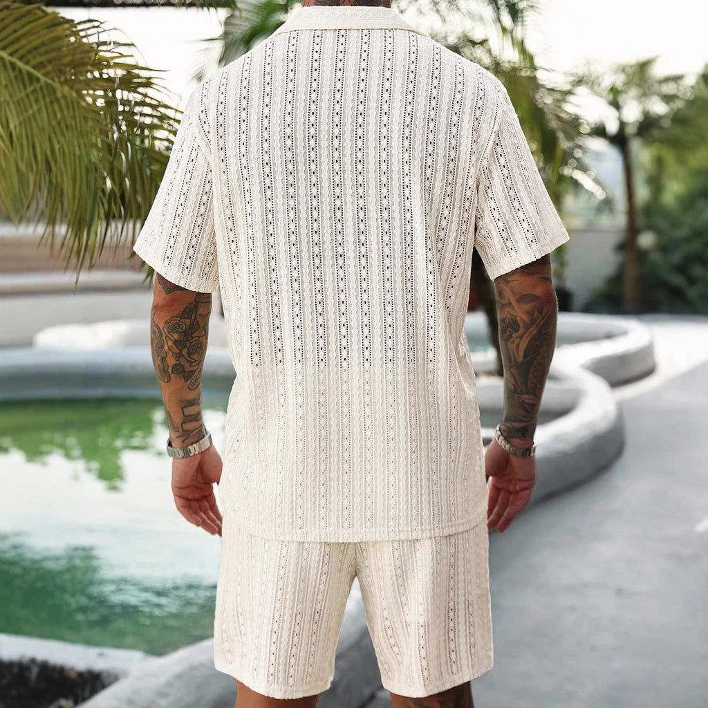 Person wearing a white patterned outfit standing by a poolside with greenery in the background
