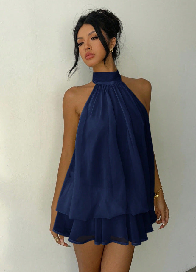 Woman wearing a navy blue halter neck dress against a plain background