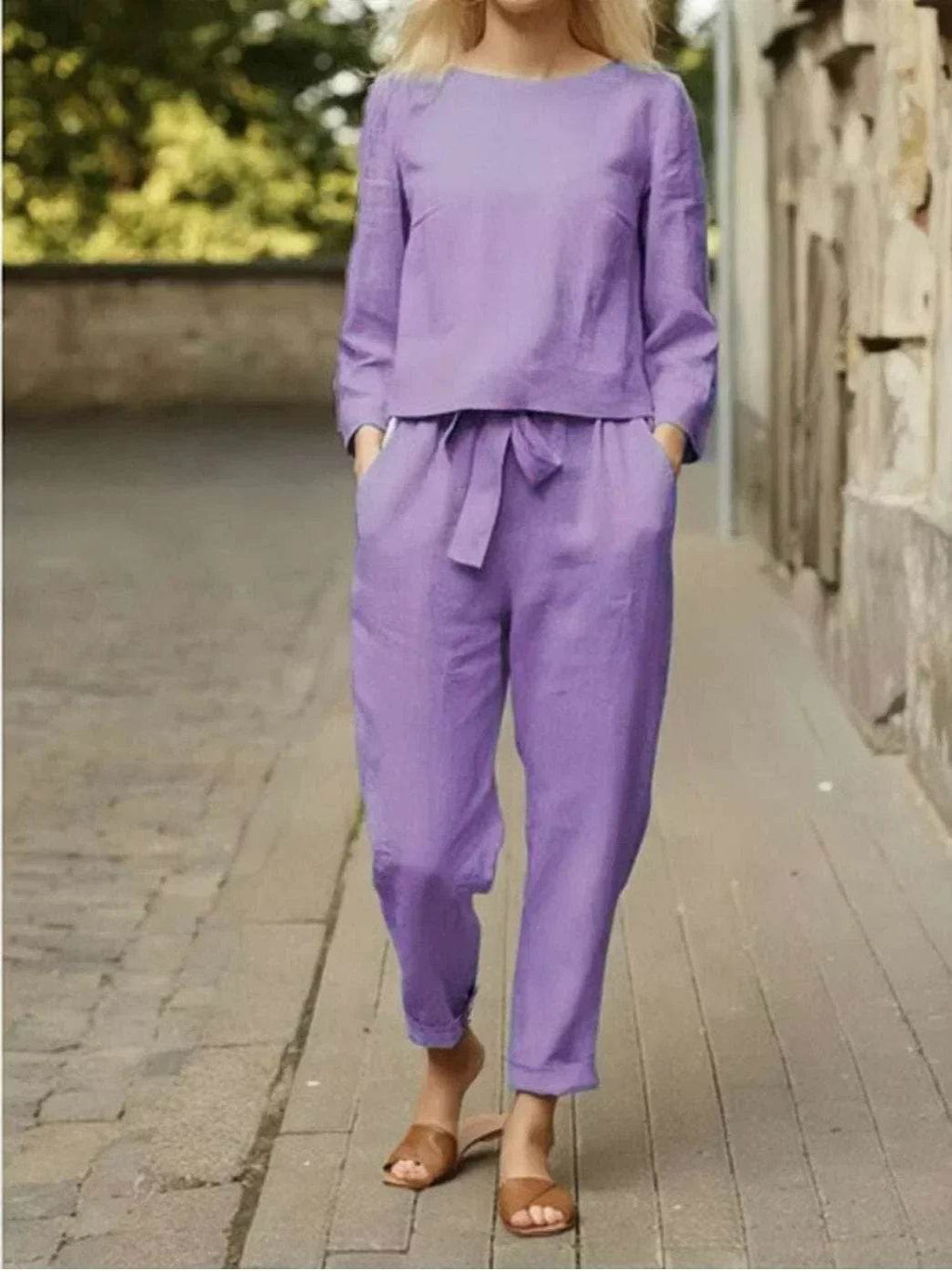 Woman wearing a lavender linen two-piece set from ZA-Zola, walking outdoors in sandals.