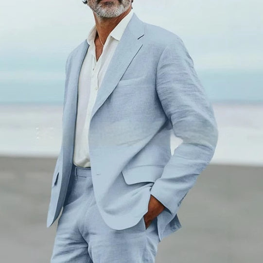 Man wearing a light gray suit with a blurred beach background