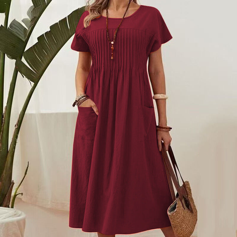 Woman wearing a burgundy dress holding a straw bag indoors.