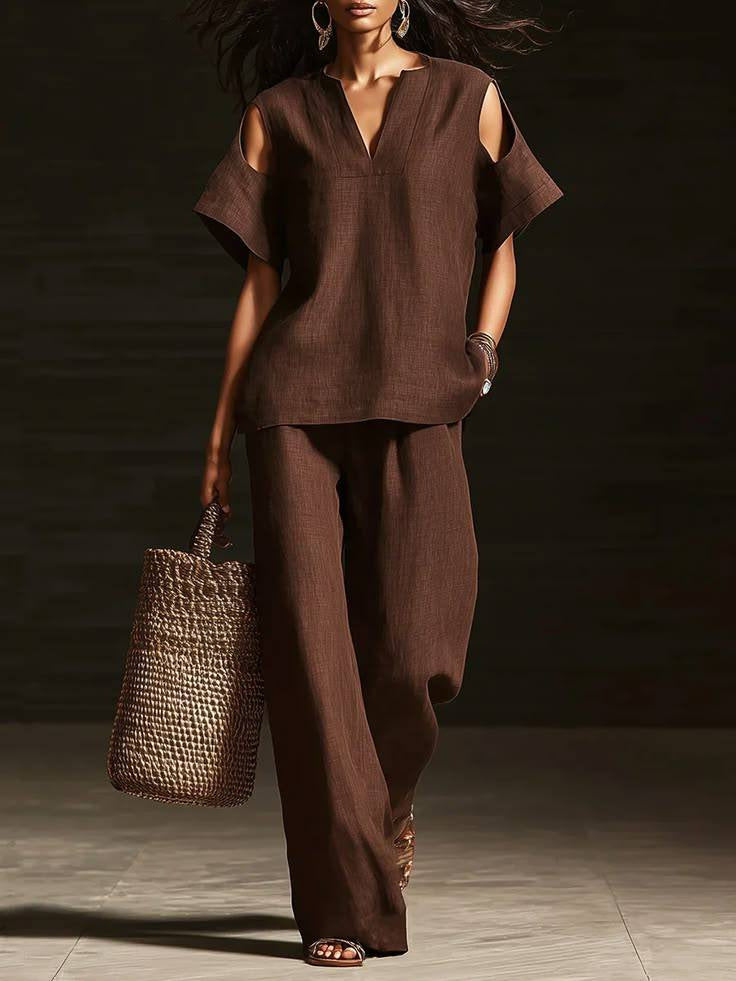 Woman in a brown outfit holding a woven bag against a dark background