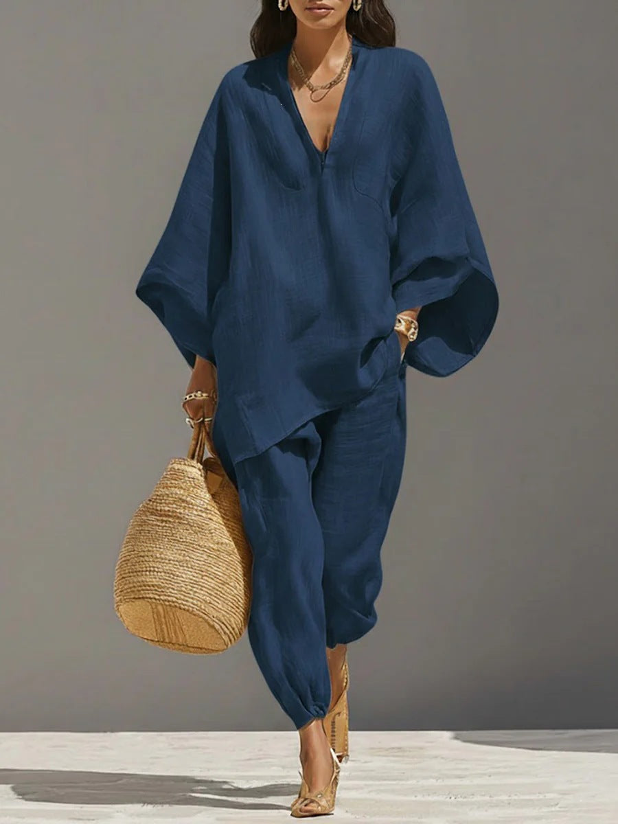 Woman wearing a blue outfit holding a straw bag against a gray background