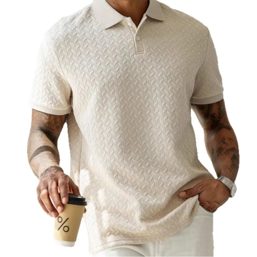 Man wearing a beige patterned polo shirt holding a coffee cup on a white background