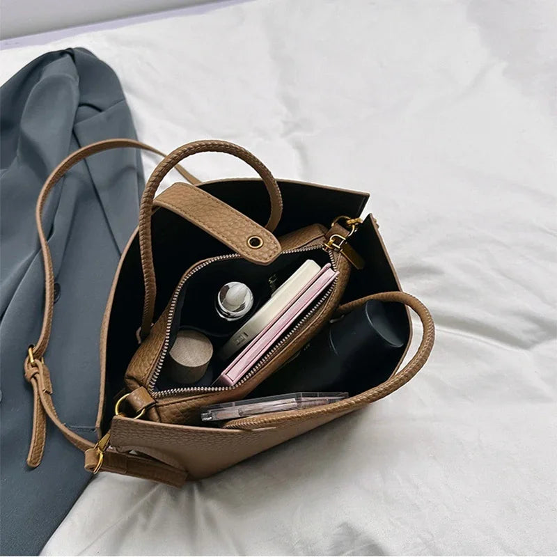Brown handbag with makeup items on a white surface