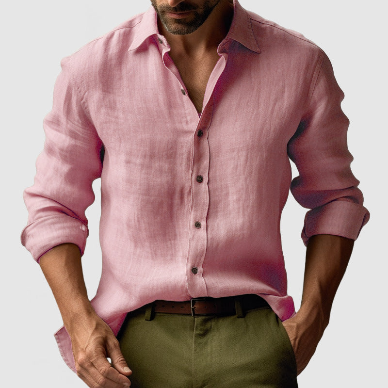 Man wearing a pink shirt with rolled-up sleeves and green pants on a light gray background