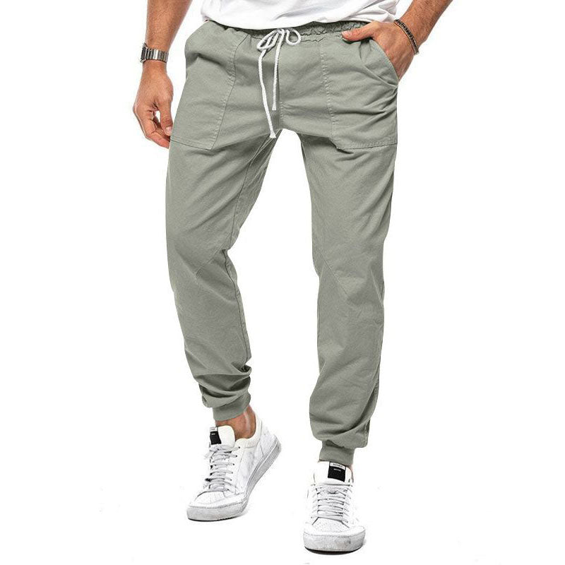 Person wearing light gray jogger pants and white sneakers on a white background