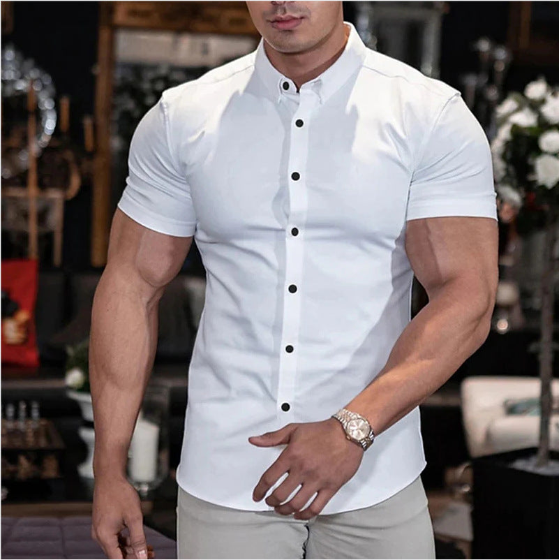 Man wearing a white short-sleeve shirt with black buttons in an indoor setting.