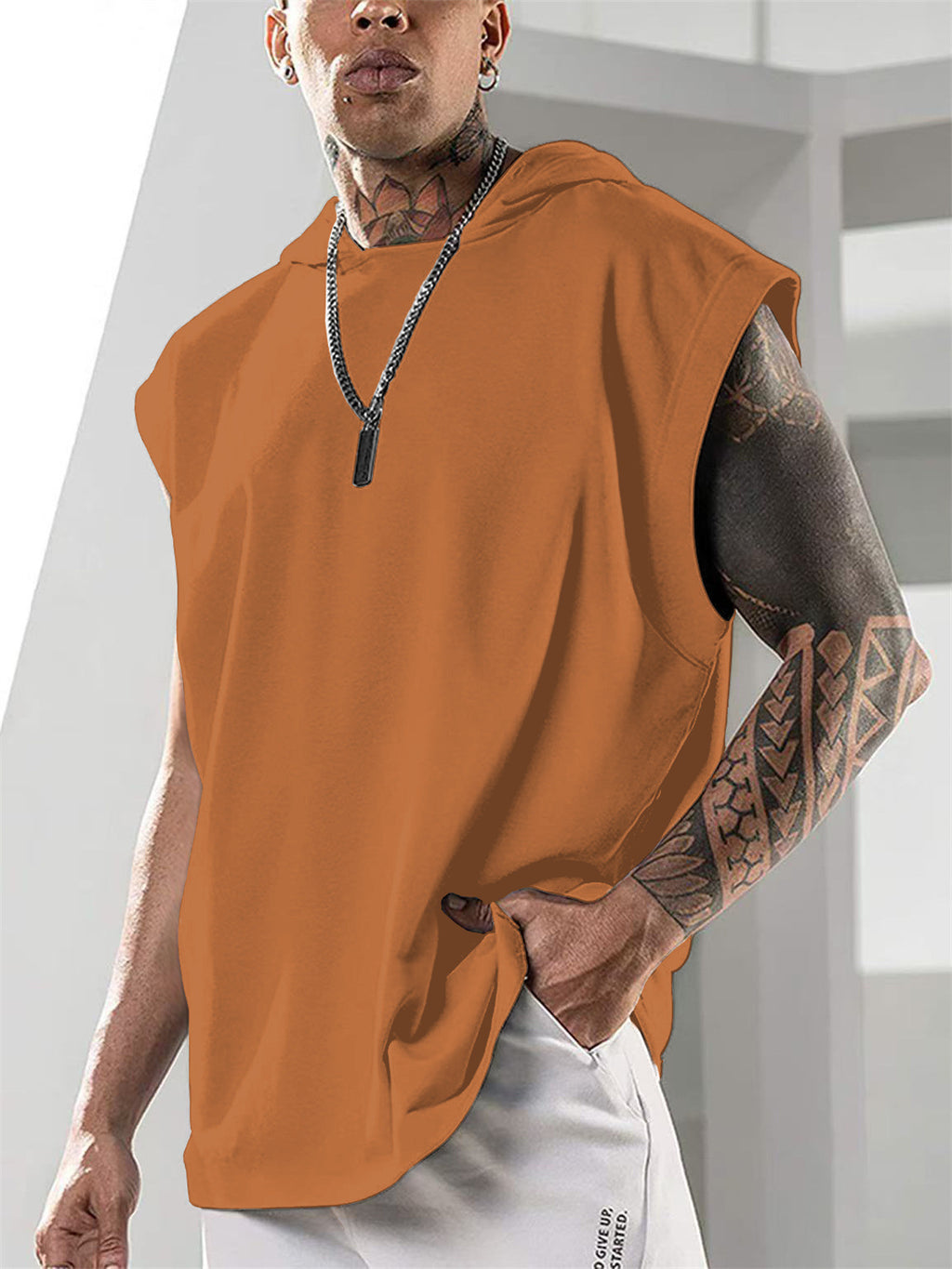 Person wearing an orange sleeveless shirt with a neutral background