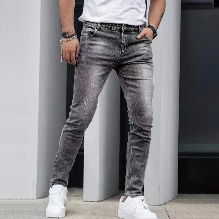 Person wearing gray jeans and white sneakers against a neutral background