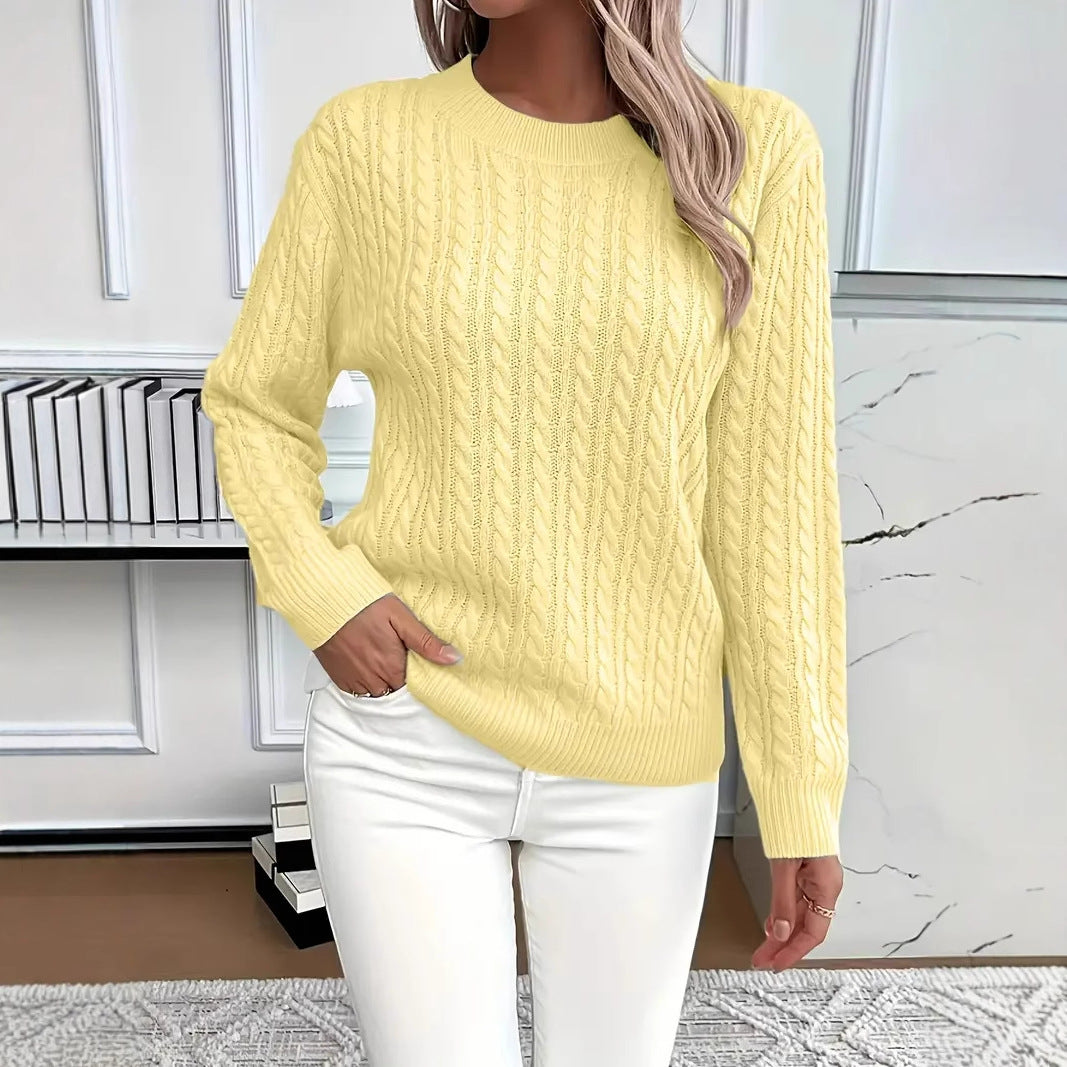 Person wearing a yellow cable knit sweater and white pants in an indoor setting.