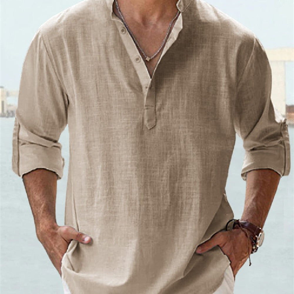 Man wearing a beige long-sleeve shirt with rolled-up sleeves against a light blue background