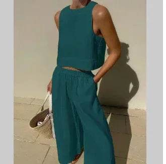 Woman wearing teal sleeveless crop top and wide-leg pants from ZA-Zola, holding a straw bag.