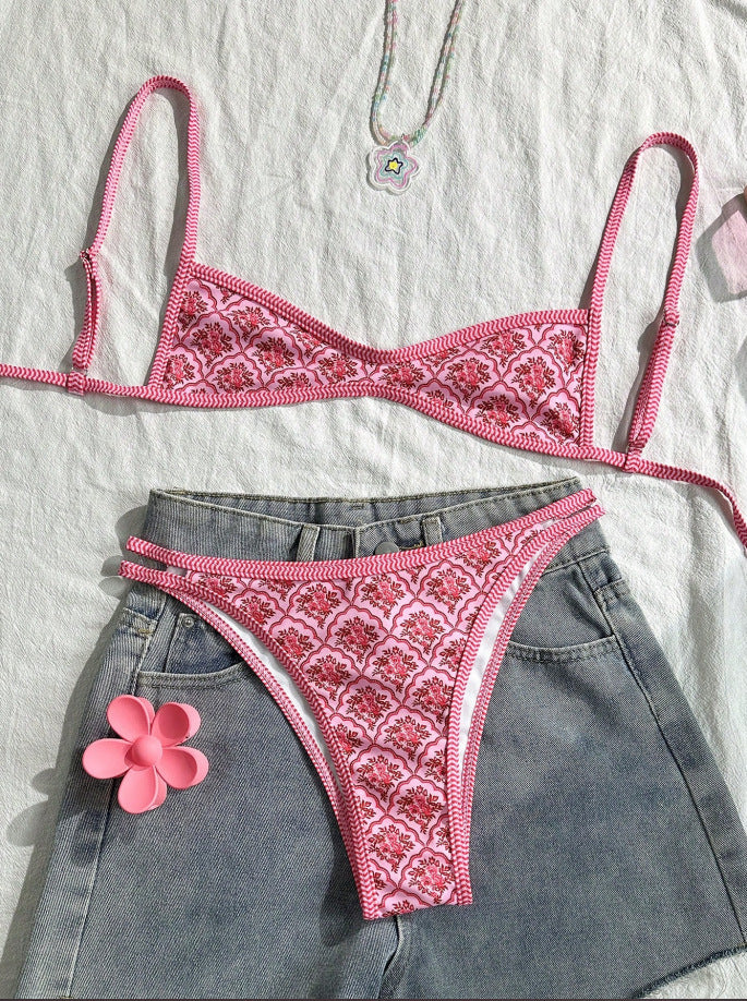 Pink embroidered bikini set on a white surface with denim shorts.