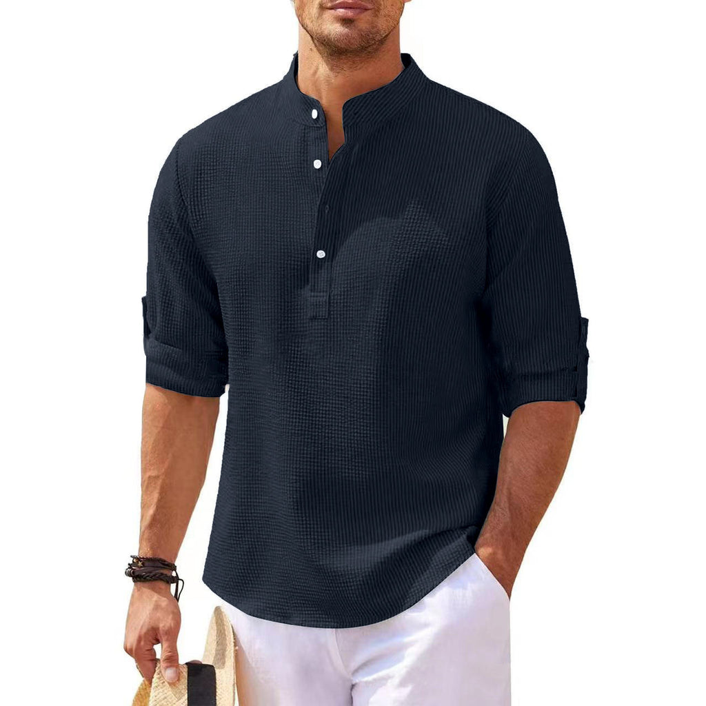 Man wearing a dark blue textured shirt with rolled-up sleeves on a white background