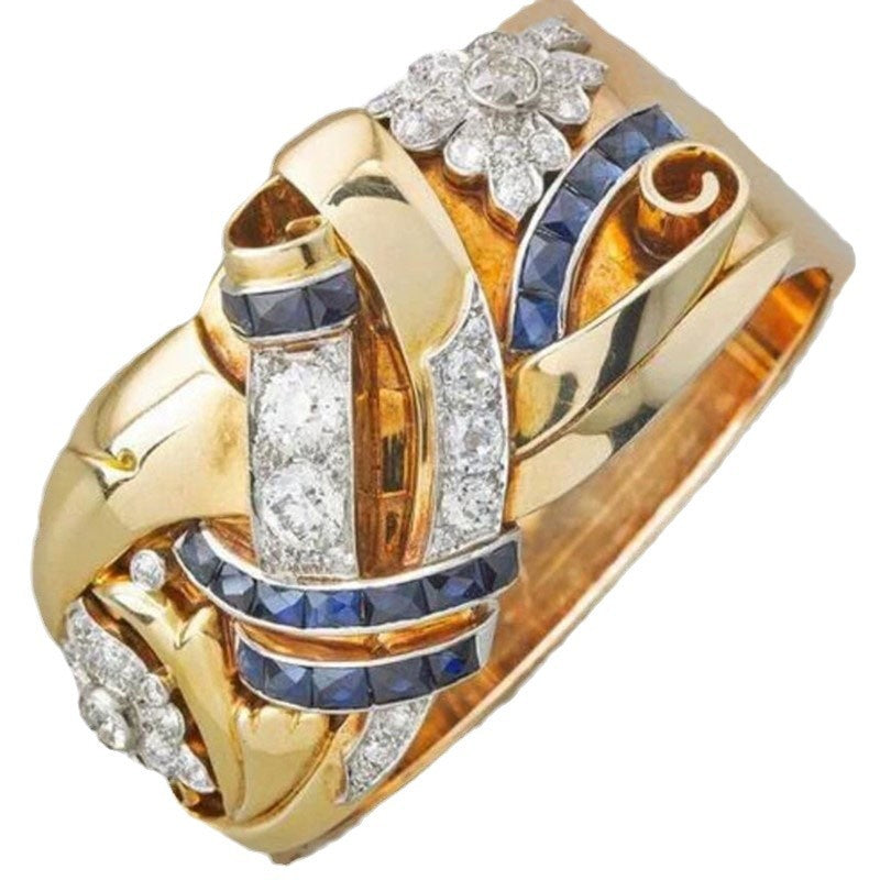 Gold ring with diamonds and blue gemstones on a white background