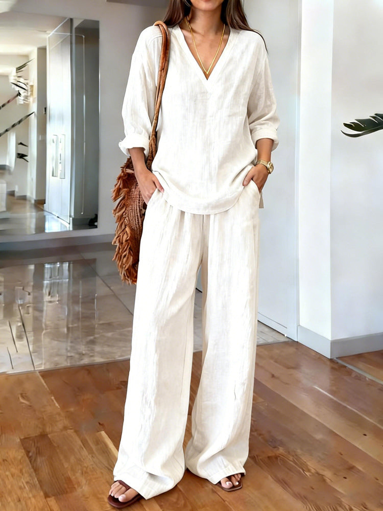 Woman wearing a white outfit with wide-leg pants in an indoor setting.
