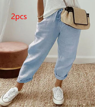 Person wearing light blue jeans and white sneakers with a beige bag, standing on a carpeted floor.