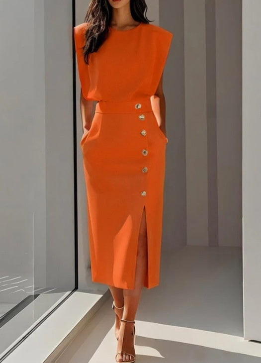 Woman wearing an orange dress with a button detail in a modern indoor setting.