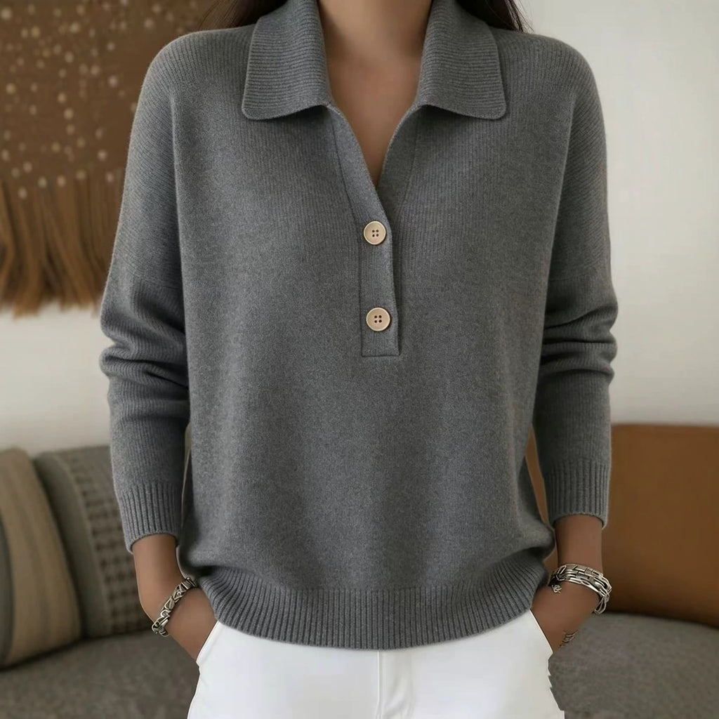 Person wearing a gray sweater with button details in a casual setting