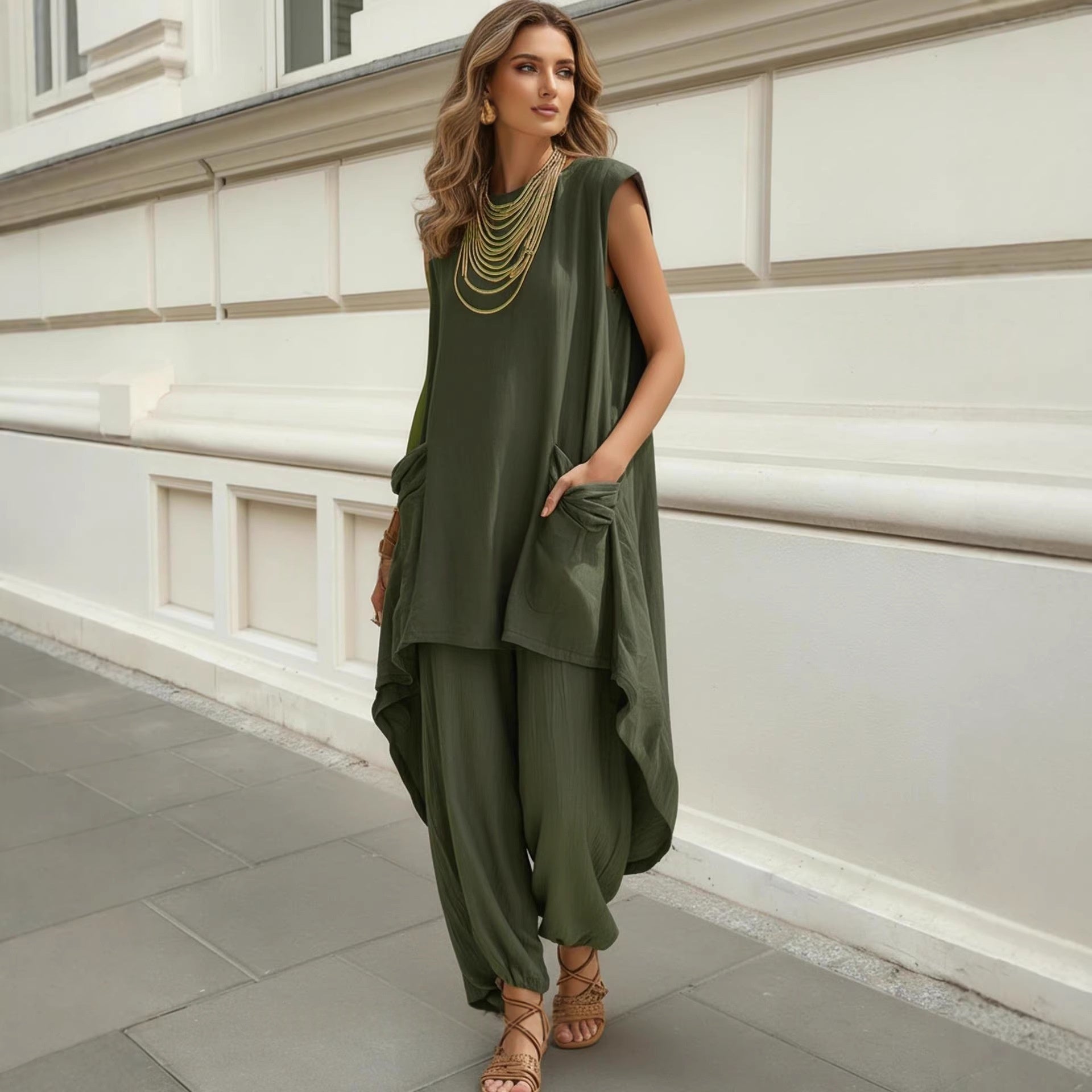 Woman wearing a green outfit standing against a white wall.