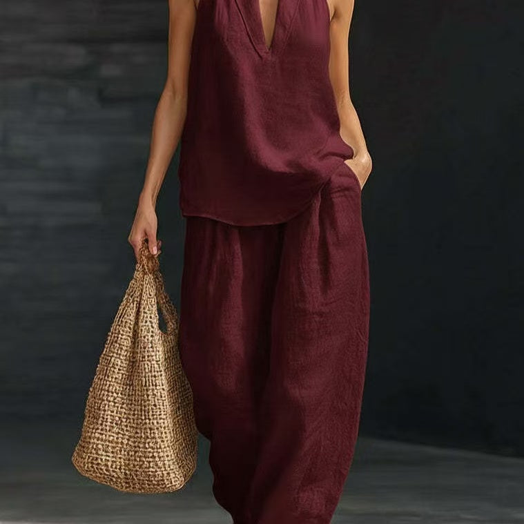 Person wearing a burgundy outfit holding a woven bag against a dark background