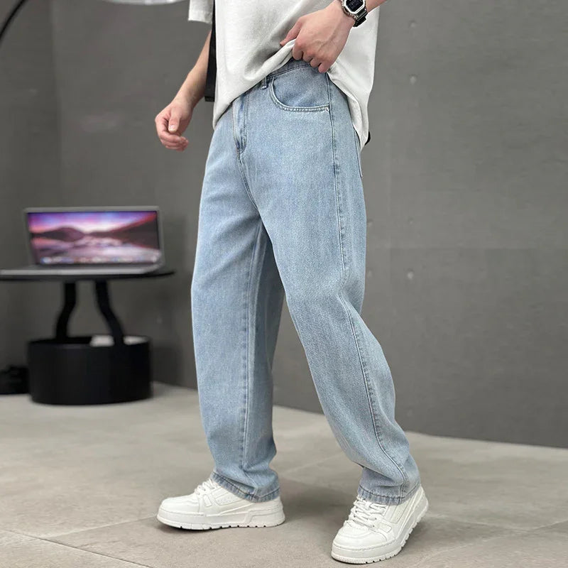 Person wearing light blue jeans and white sneakers in a studio setting with a laptop in the background.