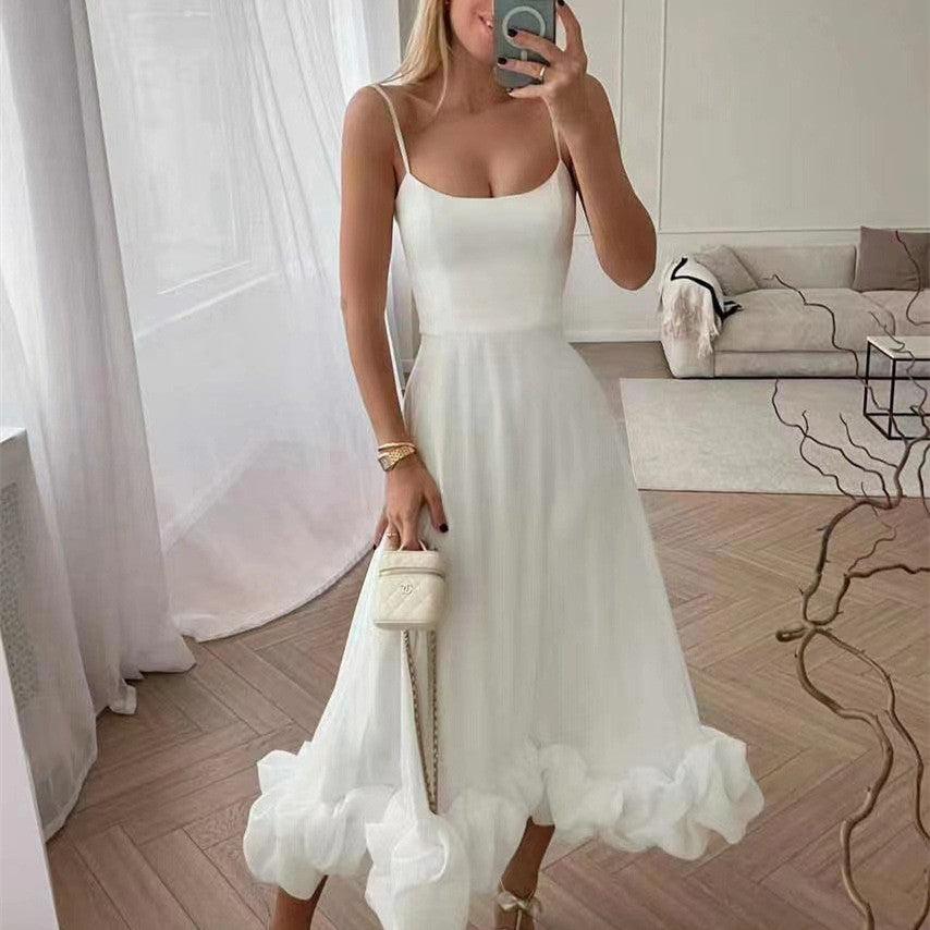 Woman in a white dress taking a mirror selfie in a room with a couch and decorative items.
