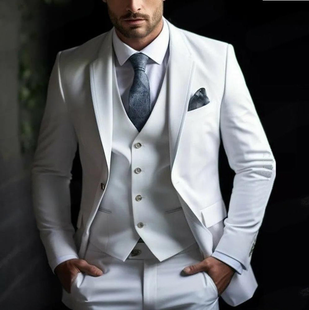 Man wearing a white suit with a gray tie and pocket square against a dark background
