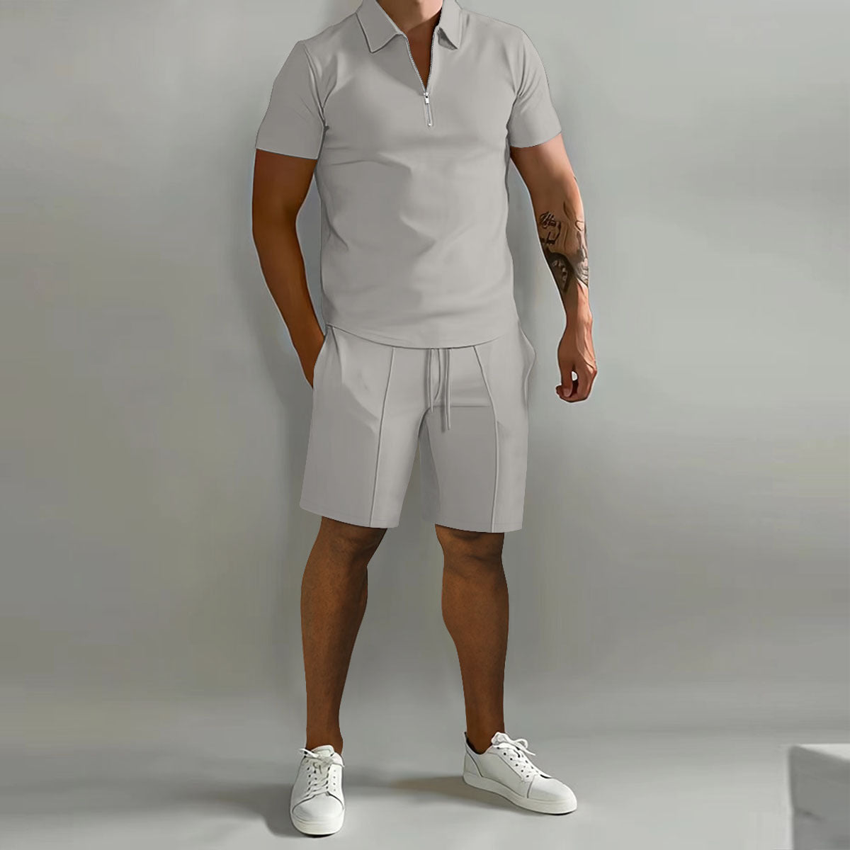 Person wearing a light gray polo shirt and shorts set with white sneakers on a plain background