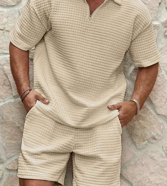 Person wearing a beige textured outfit against a stone wall background