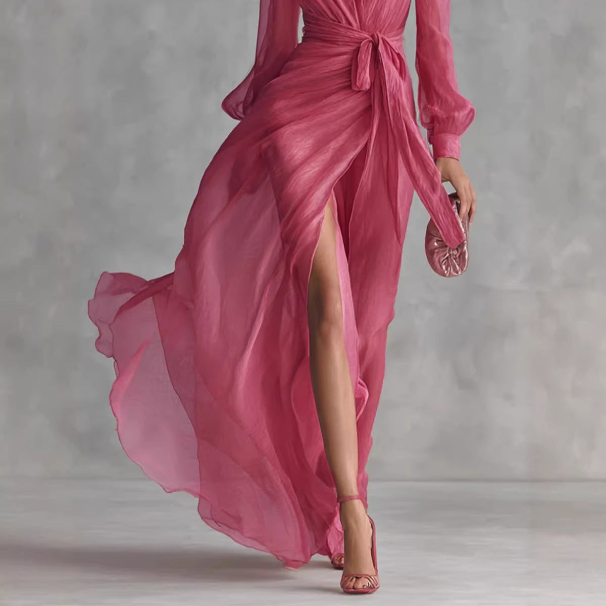 Pink dress with a high slit and matching clutch against a gray background