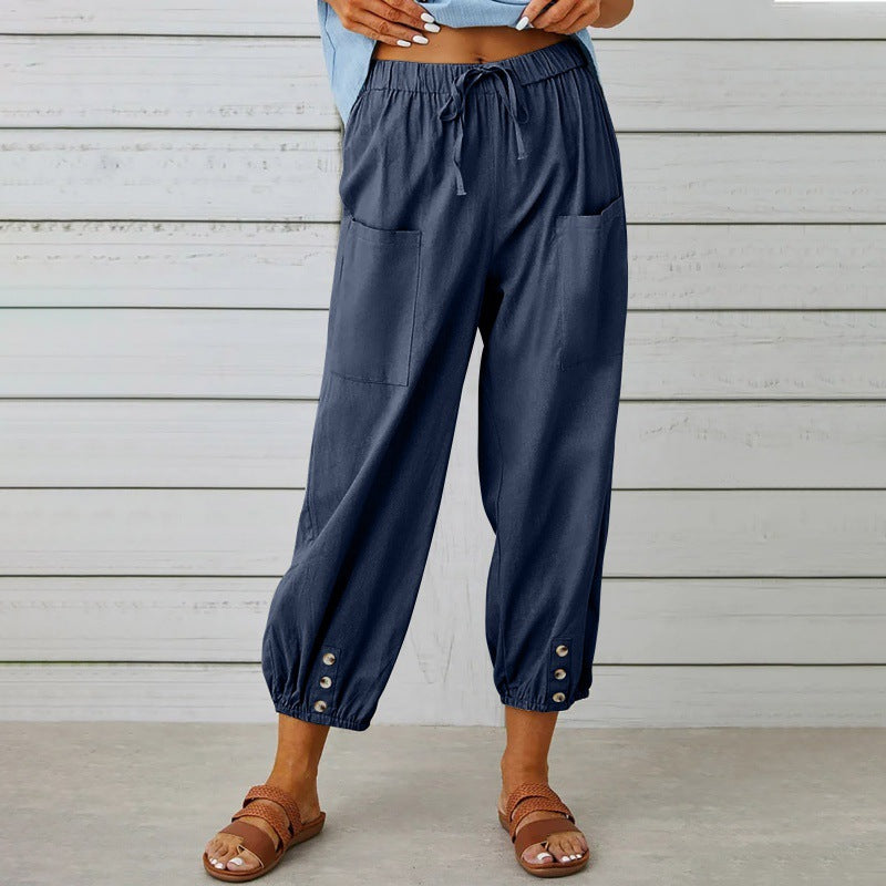 Navy blue pants with button details worn by a person against a wooden background