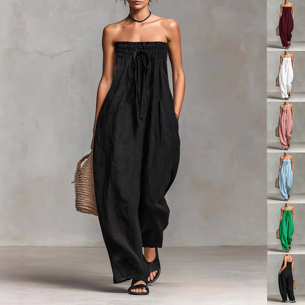 Woman wearing a black strapless jumpsuit against a gray background with a side view of the outfit.