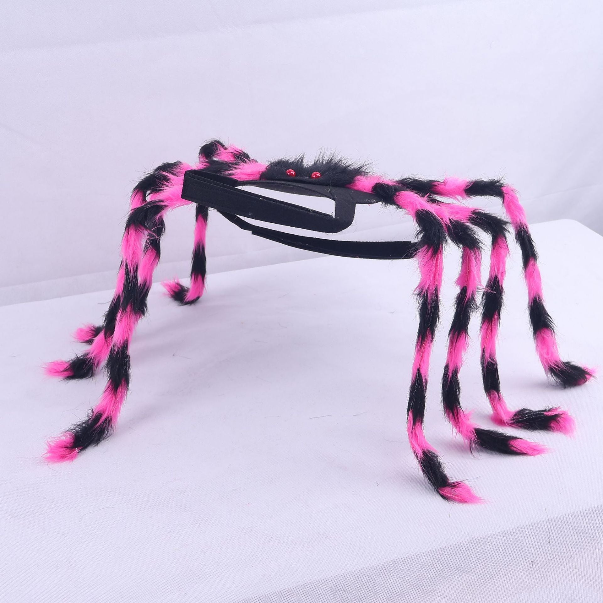 A Halloween spider costume accessory with eight fluffy black and hot pink legs attached to a black headband, featuring small red plastic eyes.