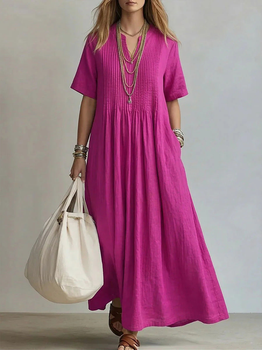 Woman wearing a long pink dress holding a white bag against a neutral background
