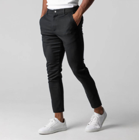 Person wearing black pants and white sneakers on a gray background