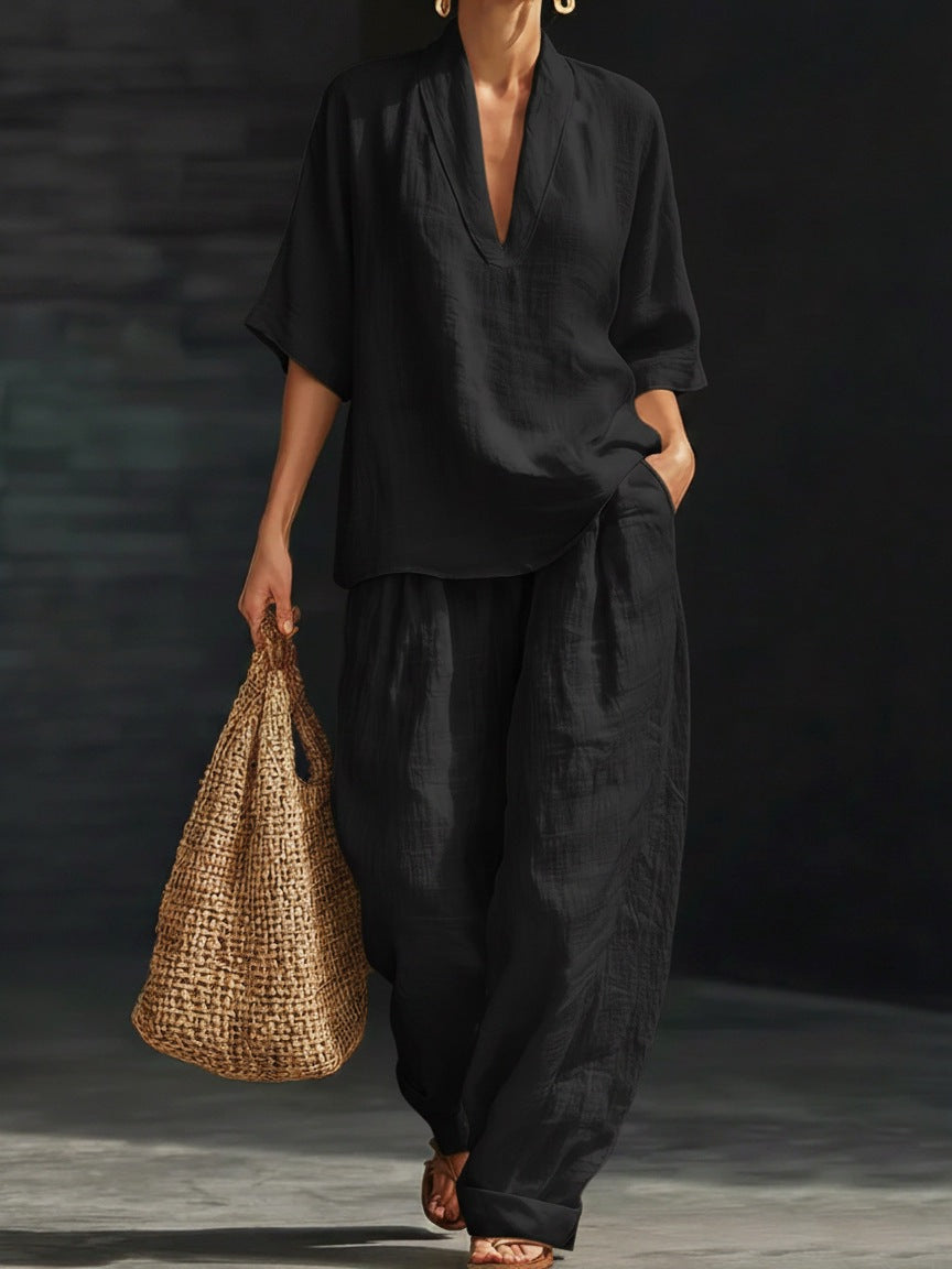 Person wearing a black outfit holding a woven bag against a dark background