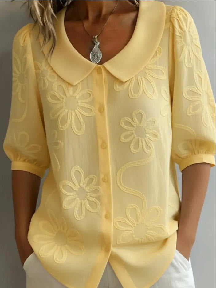 Yellow blouse with floral embroidery on a plain background