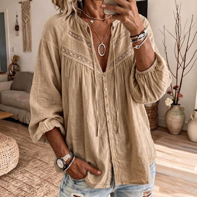 A woman takes a mirror selfie wearing a beige linen button-up blouse with lace embroidery on the chest and sleeves, paired with distressed light blue jeans.