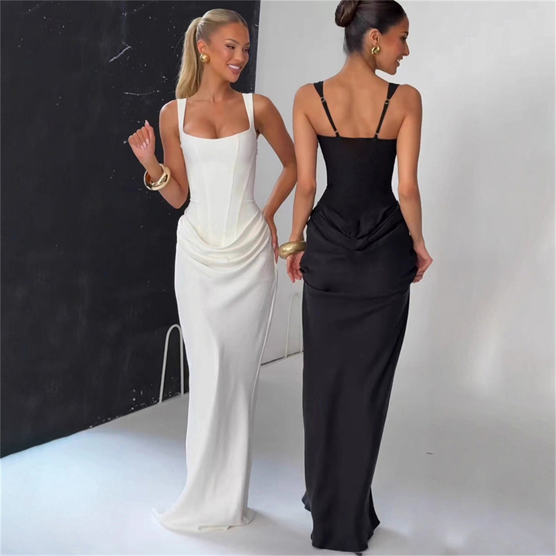 Two women wearing elegant evening gowns, one white and one black, against a neutral background.
