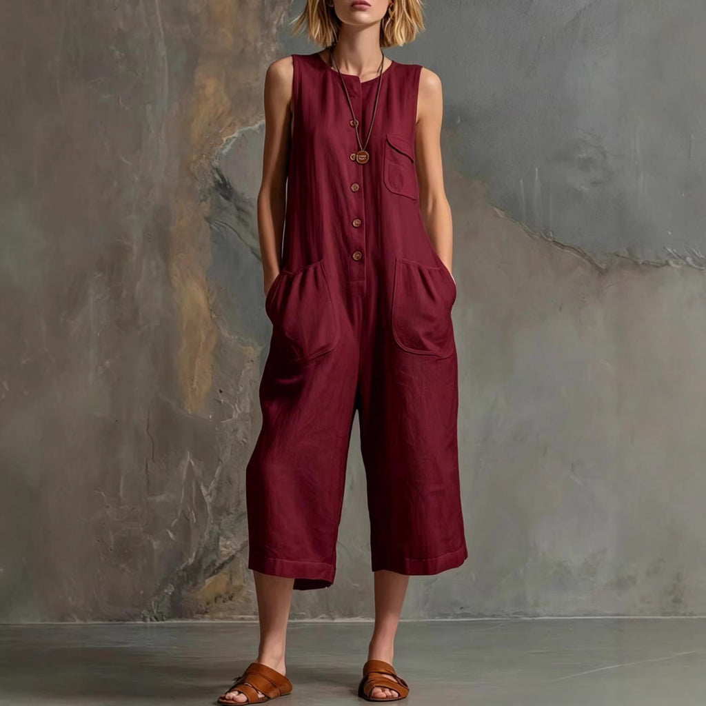 Person wearing a maroon sleeveless jumpsuit against a textured wall.