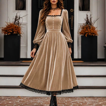 Woman wearing a beige dress with black lace trim standing in front of a door.