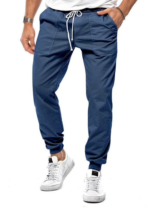 Person wearing blue jogger pants and white sneakers on a white background