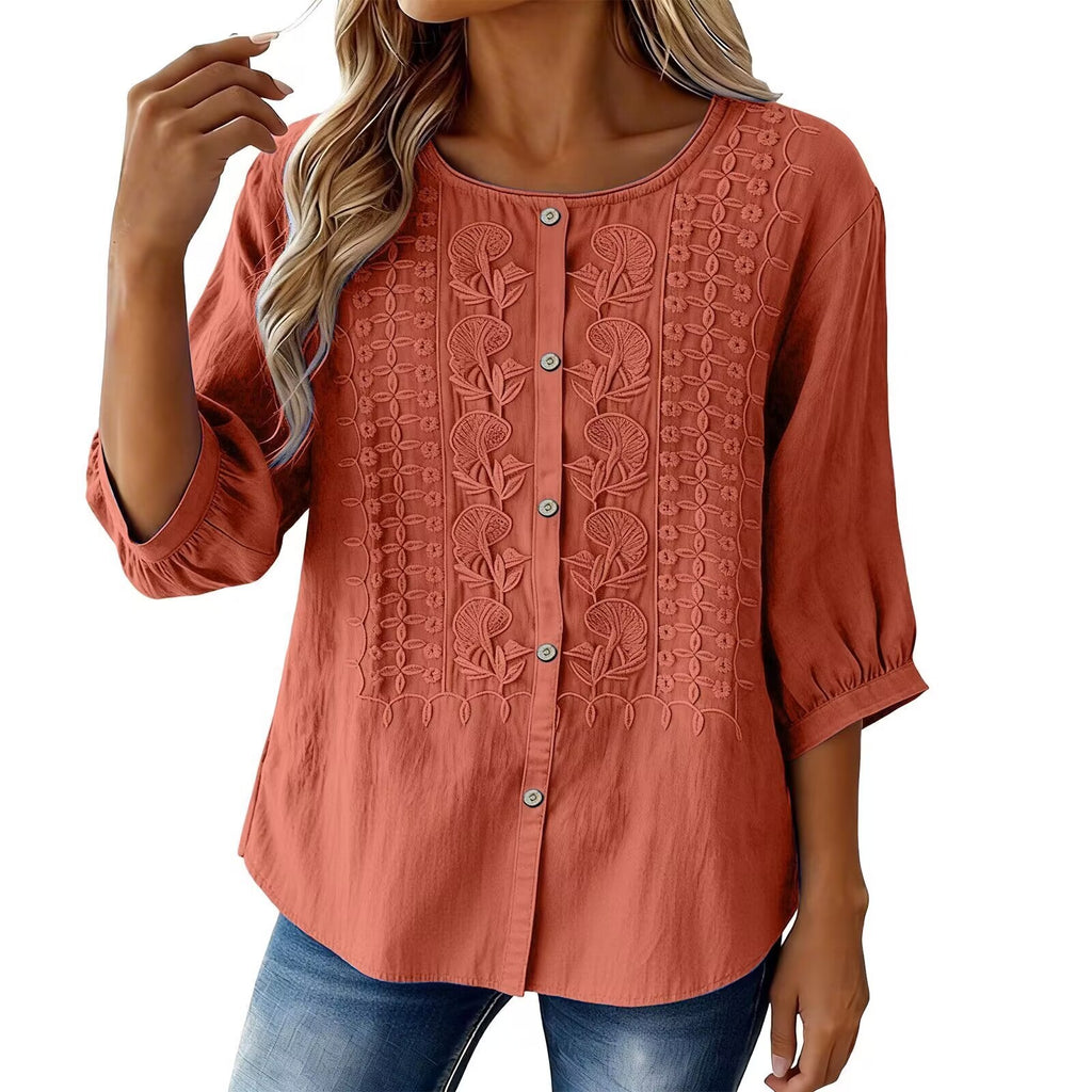 Woman wearing a rust-colored blouse with intricate patterns on a white background
