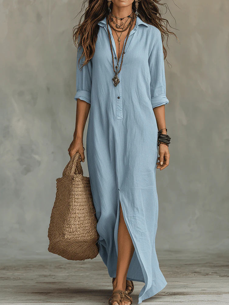 Woman wearing a long light blue dress holding a woven bag against a neutral background