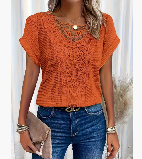 Person wearing an orange crochet top and blue jeans with a neutral background