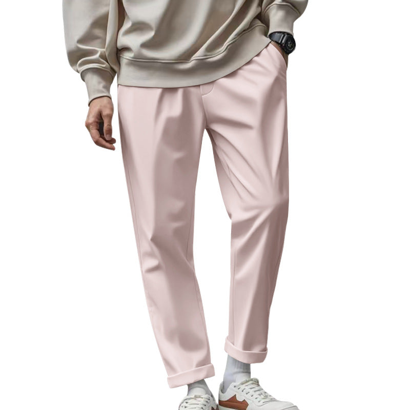 Person wearing light pink pants and a beige sweatshirt on a white background